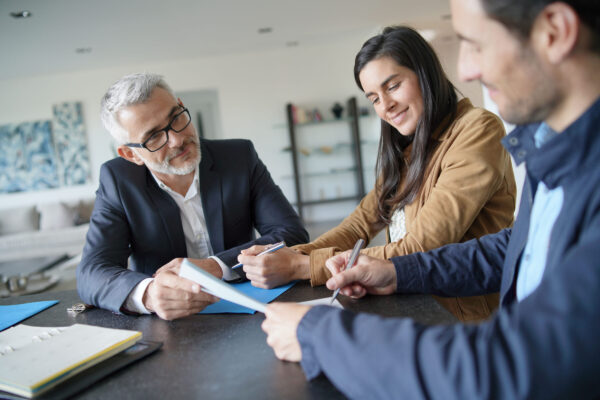 Attractive couple signing contract with real-estate agent in contemporary house