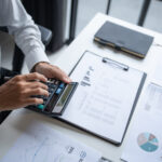 Businessman Calculating Finances with Calculator in Modern Office.